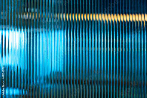 Abstract creative image on patterned glass show vertical lines pattern repetition blurry background of wavy illuminated multi-colored interior soft lighting.glass surface used for artistic backdrop. photo