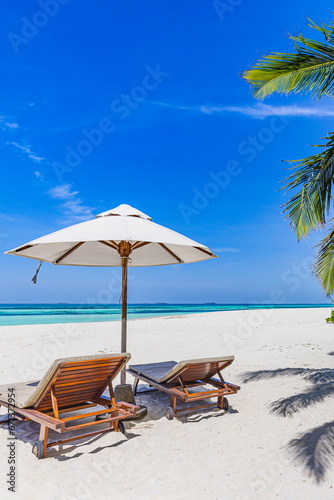 Tropical paradise beach white sand coconut palm trees majestic sea. Vertical panorama romantic chairs umbrella sunny landscape. Luxury vacation holiday banner tropical resort. Beautiful coast serene