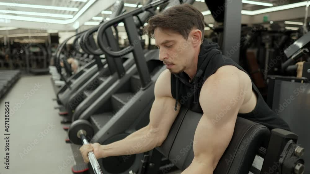Bodybuilder trainer doing Scott barbell bicep curl in slow motion at fitness center - medium shot, slow motion Bodybuilder trainer doing Scott barbell bicep curl in slow motion at fitness center - medium shot, slow motion