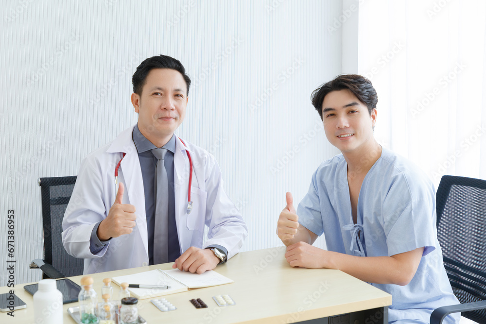 Male doctor and young male patient while consult and explain. Doctor and patient sitting together  at table in clinic.