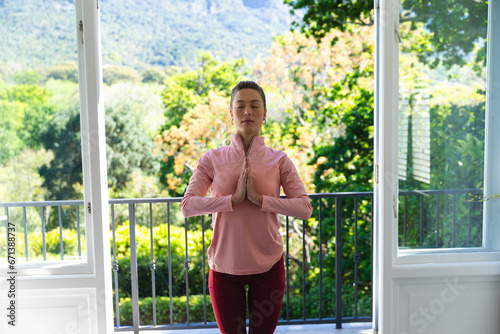 Free Download Focused caucasian woman in sport clothes practising yoga in sunny room at home - GFXLoad