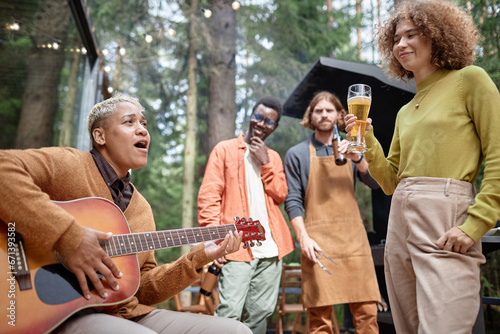 Group of young friends playing guitar and drinking beer at picnic in the forest © AnnaStills