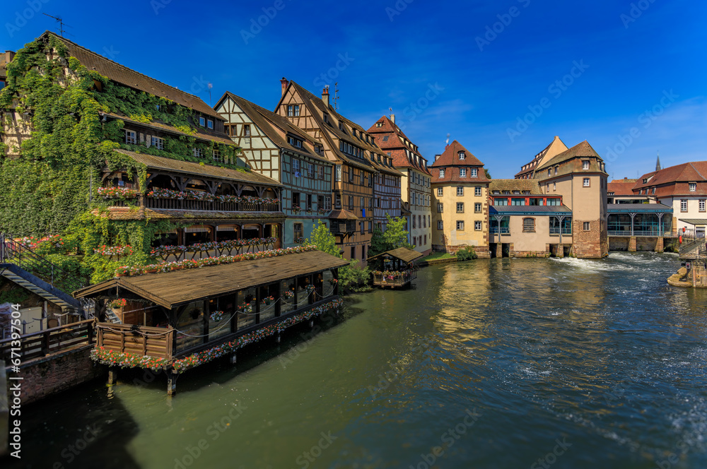 Ornate traditional half timbered houses with blooming flowers along the canals in the picturesque Petite France district of Strasbourg, Alsace, France	