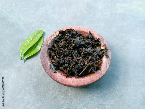 green tea leaves. Tea dregs in wooden bowl on gray background. wet tea leaves
