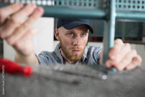 man with handtools assembling metal framework