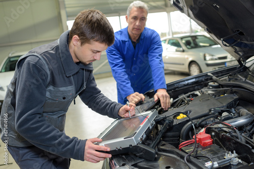 auto mechanic teacher and trainee performing tests at mechanic school