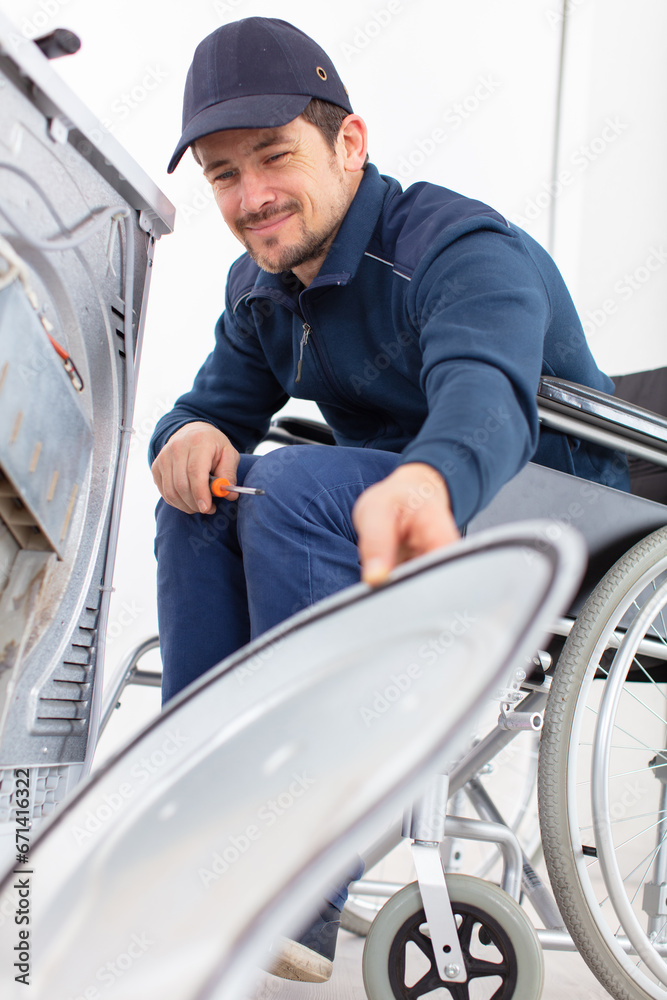 washing machine repairman in wheelchair dismantles machine