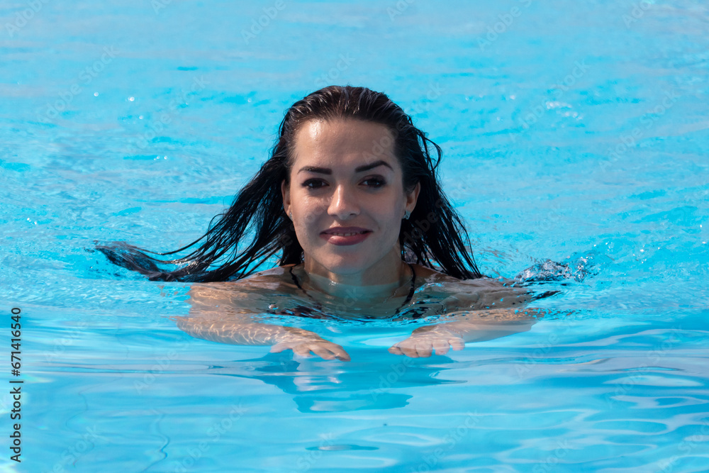 Portrait of a woman floating in the blue water of a pool