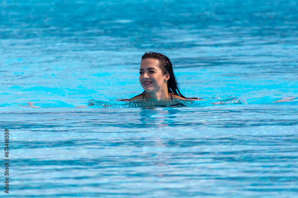Portrait of a woman floating in the blue water of a pool