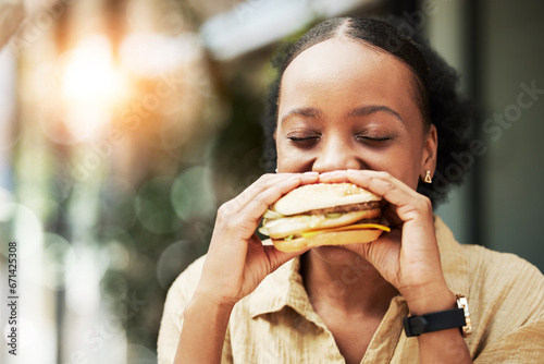Happy  fast food and black woman eating a sandwich in an outdoor restaurant as a lunch meal craving deal. Breakfast  burger and young female person or customer enjoying a tasty unhealthy snack