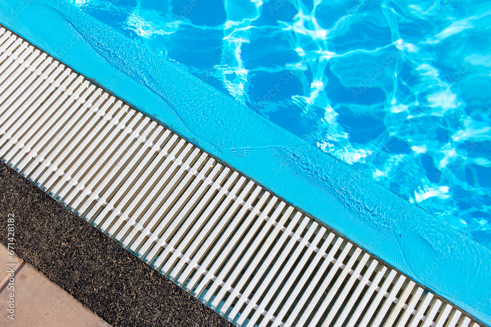 The edge of a swimming pool with blue water as an abstract background