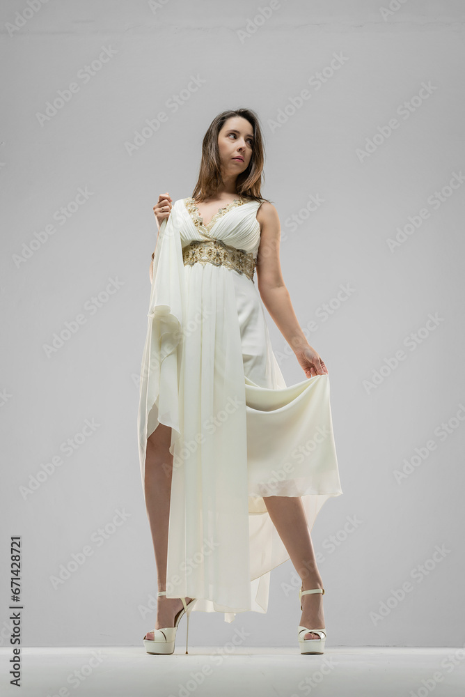 Naklejka premium Woman in the retro style white dress posing on the white background.