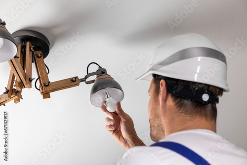 handyman services. electrician replace led light bulb in ceiling lamp at home photo
