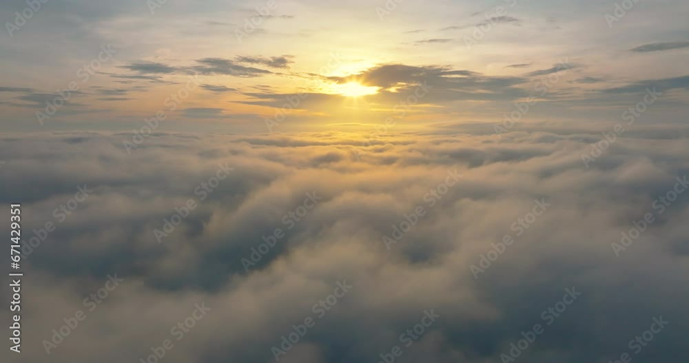 Aerial4K drone in sky is raising above from the thick fog above the beautiful ocean of clouds at sunrise. Sun is rising above the endless sea of clouds until the horizon. Amazing nature landscape