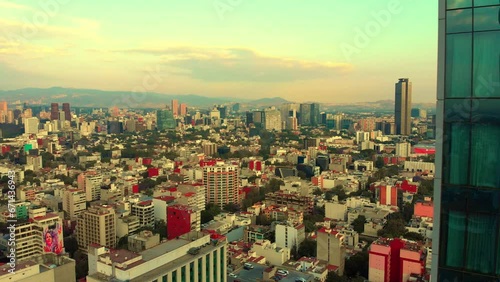 Drone revealing cityscape behind tall building urban neighborhood Mexico City morning light clear sky photo