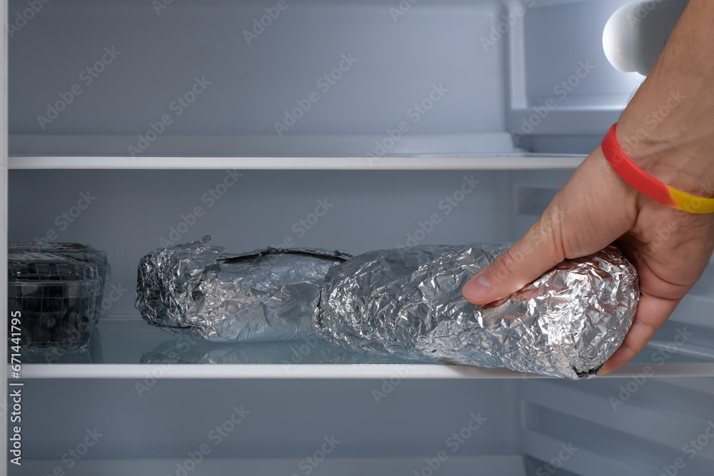Domowa kanapka zawinięta w folię aluminiową odkładana na półkę w lodówce  - obrazy, fototapety, plakaty 