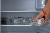 Domowa kanapka zawinięta w folię aluminiową odkładana na półkę w lodówce 