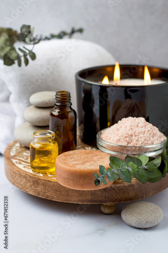 Spa set on a wooden stand, eucalyptus branches, aroma oils, candles and stones. Spa treatments, massage, relaxation and beauty concept.