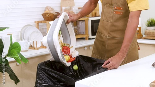 Unrecognizable hand of worker male or chef wearing apron cleaning the kitchen throwing away waste foods and dirty vegetables to trash in modern kitchen, housework or hygiene clean table in apartment