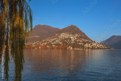Sunset autumnal panorama of Lugano city overlooking the homonyms lake with trees of Parco Ciani in autumnal colors and Mount Brie in the background. Lugano, Ticino, Switzerland photo