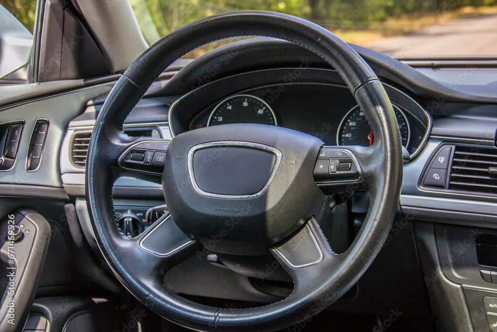 Black leather steering wheel and car dashboard close-up
