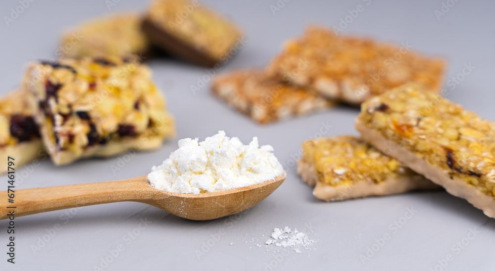 Whey protein powder in spoon and different energy protein bars on grey background. Close-up. Selective focus.