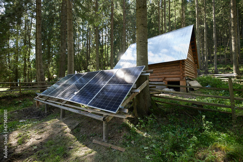 Solar panels in a coniferous forest in the mountains on the background of a log house.