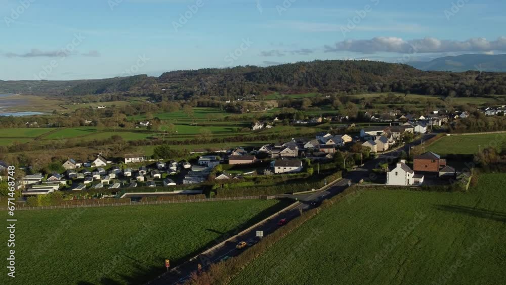 Aerial view orbiting over small town Welsh community farmland with Snowdonia mountain range on the horizon Aerial view orbiting over small town Welsh community farmland with Snowdonia mountain range on the horizon
