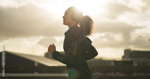 Woman, morning and running in city with headphones for fitness, workout and marathon training music. Sun lens flare, athlete or exercise podcast in Brazil for cardio wellness, health or sports radio photo