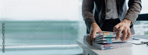 Preparing documents to attend the meeting, Checking documents that employees have brought in the office, Arrange printed information into relevant categories. photo