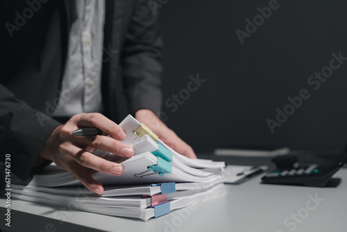 Preparing documents to attend the meeting, Checking documents that employees have brought in the office, Arrange printed information into relevant categories. photo