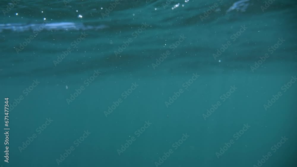Sun-lit sea with mild waves, recording a dive under followed by a resurfacing in slow motion. Sun-lit sea with mild waves, recording a dive under followed by a resurfacing in slow motion.