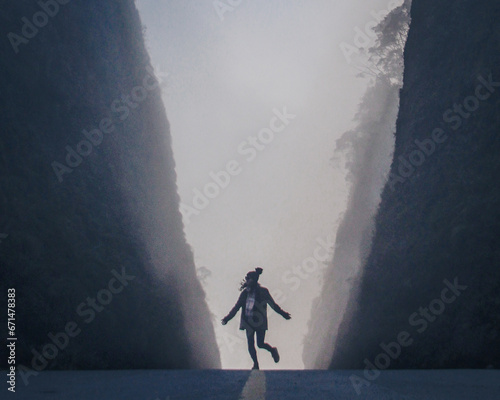 silhueta de mulher caminhando entre paredões da serra do corvo branco, entre urubici e grão pará, santa catarina photo
