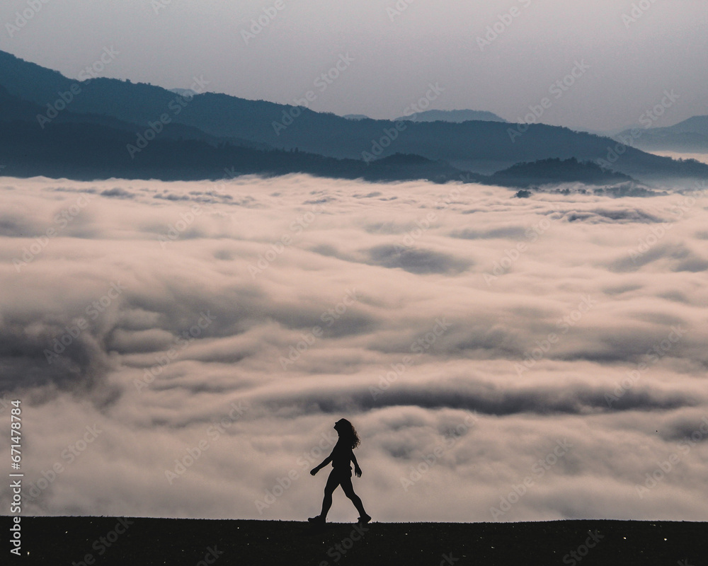 silhueta de mulher caminhando com mar de nuvens ao fundo em rio dos cedros, santa catarina 