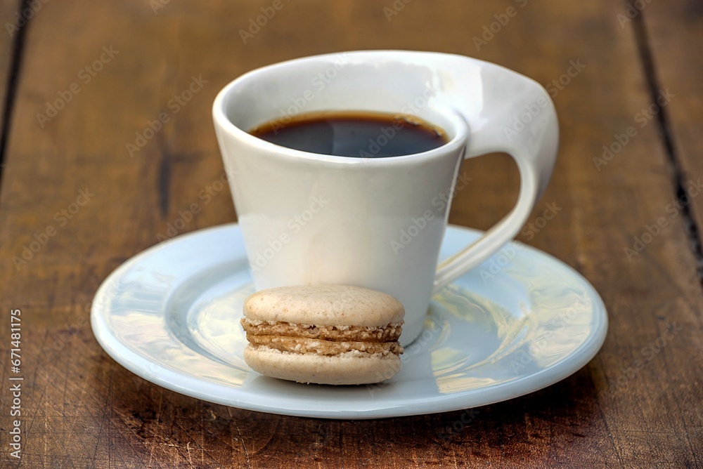 Beautiful white cup of espresso and one macaroon on wooden background close up Beautiful white cup of espresso and one macaroon on wooden background close up