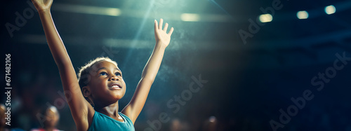 Young African gymnast raises arms in joy under spotlight in a gym. photo
