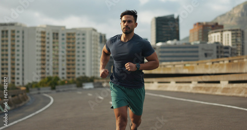 Running, city and man on road in training, endurance and fitness lifestyle for marathon competition. Indian runner, exercise commitment and body wellness for cape town race, progress and urban sport photo