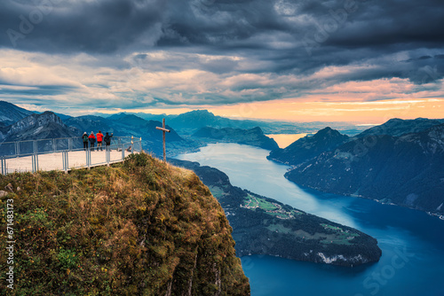 Fronalpstock with cross and tourist traveling on summit and moody sky overlooking Lake Lucerne at Schwyz, Switzerland photo