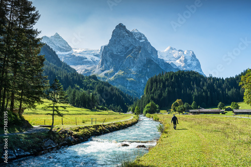 View of Rosenlaui with male tourist walking along Reichenbach river and wetterhorn glacier mountain at Bern, Switzerland