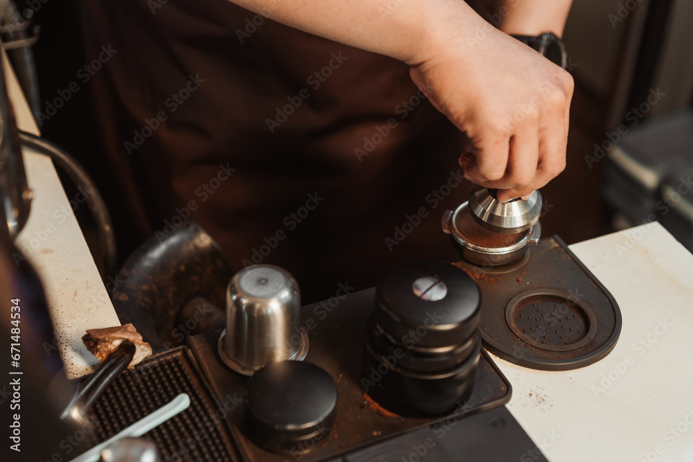 Closeup hand of barista preparation tampering coffee in portafilter for making espresso. Coffee making concept. Closeup hand of barista preparation tampering coffee in portafilter for making espresso. Coffee making concept.