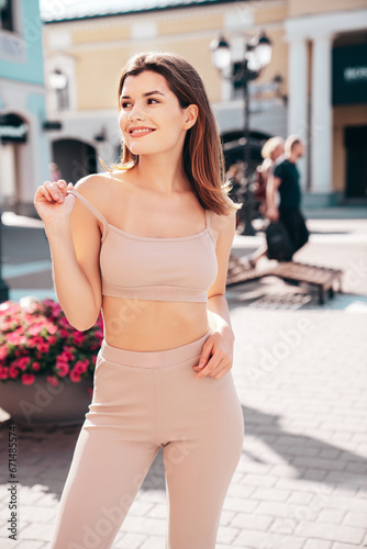 Young beautiful smiling woman in trendy summer clothes. Sexy carefree model posing on the street background at sunset. Positive brunette female. Cheerful and happy. In Europe city