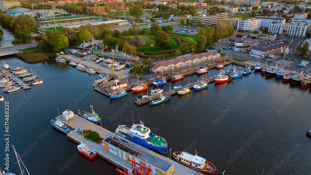 A breathtaking aerial drone photo of Kołobrzeg's marina in Poland captures a picturesque scene. The view showcases a multitude of yachts, sailboats, fishing boats and ships.
