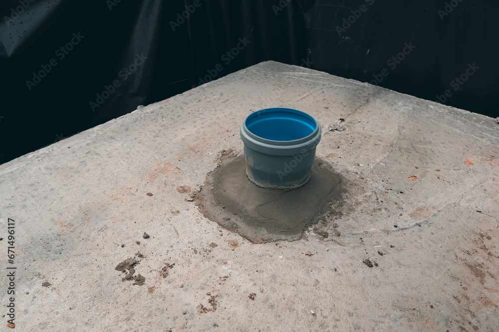 The passage of the sewage pipe through the concrete floor slab.