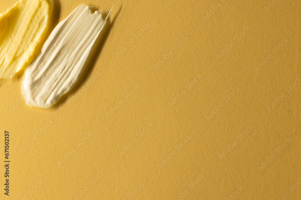 Close up of beauty product white and yellow cream smudges with copy space on yellow background Close up of beauty product white and yellow cream smudges with copy space on yellow background