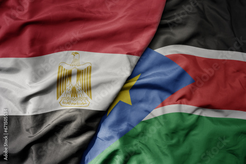 big waving national colorful flag of egypt and national flag of south sudan .