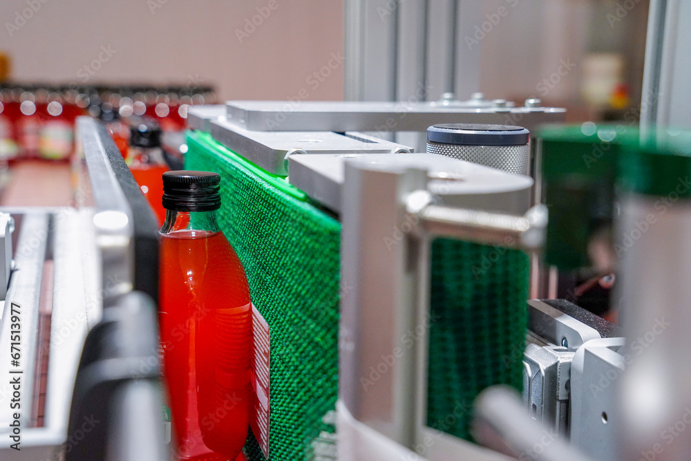 labeling process on bottles with red drink, in an industrial factory
