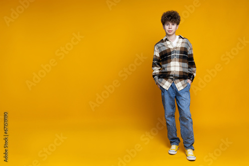 Attractive, curly boy teenager on a yellow background.
