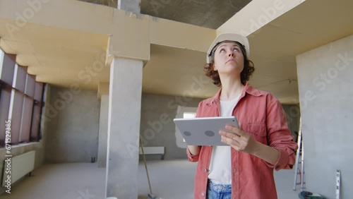Woman inspecting construction site and checking plan on digital tablet photo