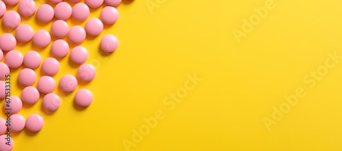 pink pills on yellow background copy space right banner. Medicine, treatment, capsule for curing disease. Pharmaceutical business and trial research. photo