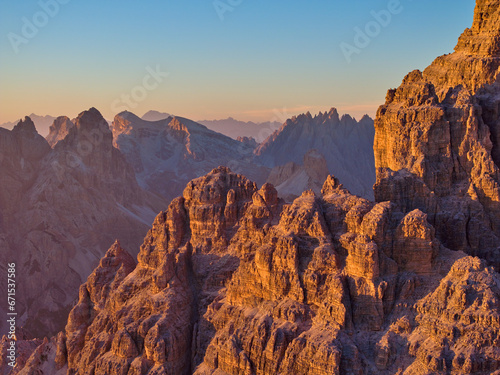 Orange lit peaks of Tre Cime, Dolomites, Italy. Aerial view, close up, views of mountains in the background. A climber's paradise.
